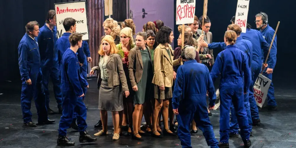 Frauen sind mit Plakaten am streiken und Männer versuchen auf sie einzureden, mit dem Stecken aufzuhören